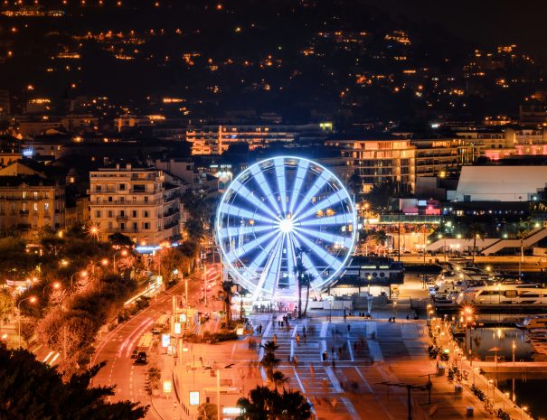 View of Cannes, France at night. Embankment street, ferris wheel, nightlights, moored yachts